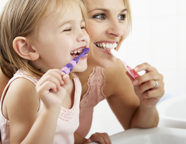 woman brushing teeth with her child