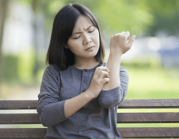 Woman on bench scratching her arm