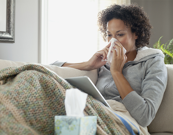 woman sitting on couch blowing her nose