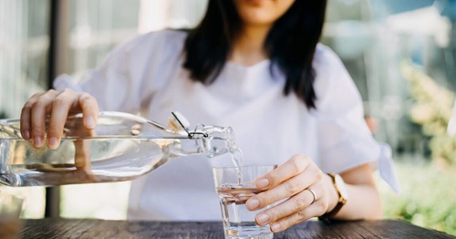 Woman pooring herself a glass of water to stay hydrated