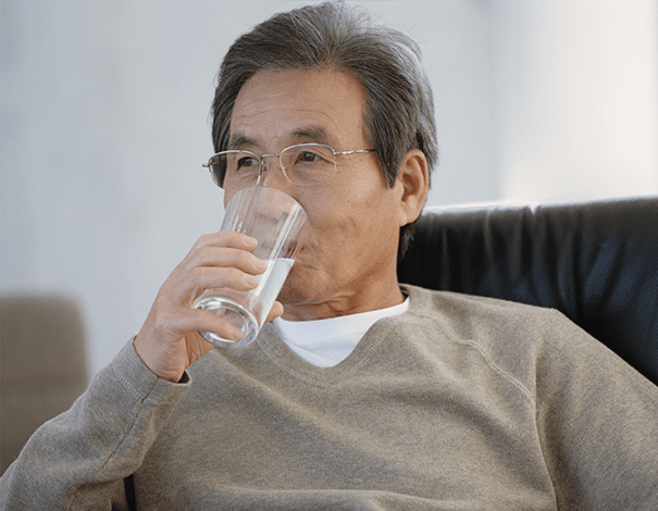Pensive man drinking a glass of water on couch