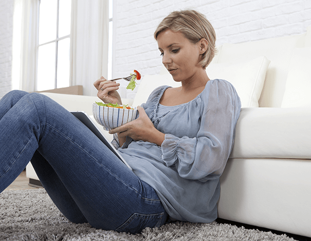 Woman sitting on the ground eating a bowl of fruit