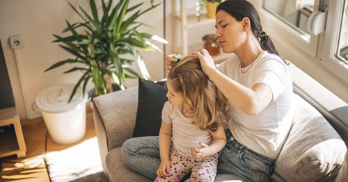 Mother brushing the hair of her daugther, in the living room