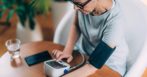 Adult woman measuring her blood pressure with a monitor