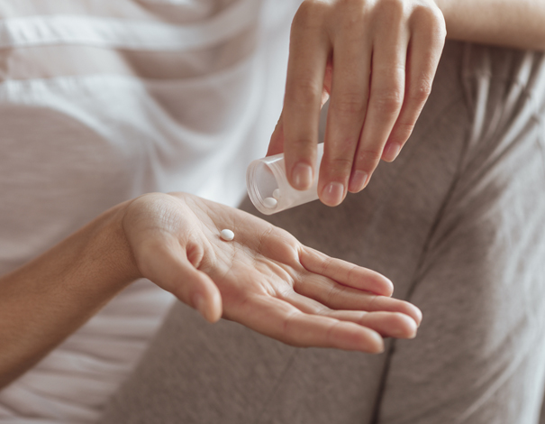 woman taking pill from her bottle