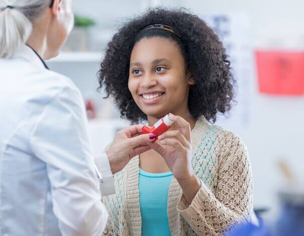 teenage girl receiving inhaled medication from pharmacist