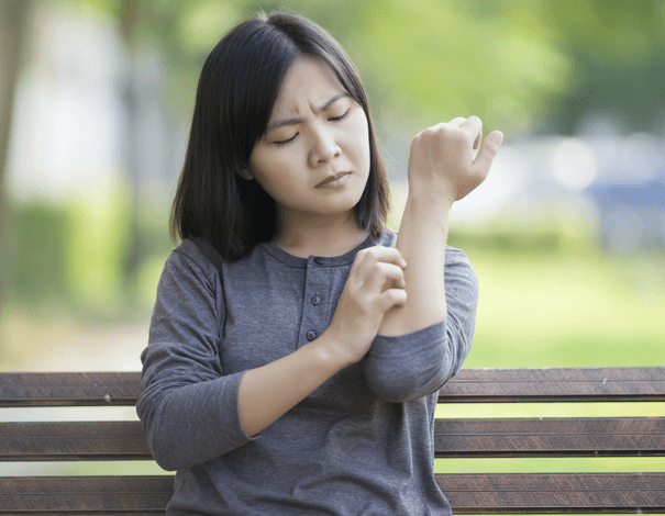 Woman on bench scratching her arm Woman on bench scratching her arm
