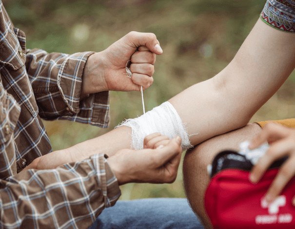 Someone putting a bandage on a person's hurt arm using a first aid kit Someone putting a bandage on a person's hurt arm using a first aid kit