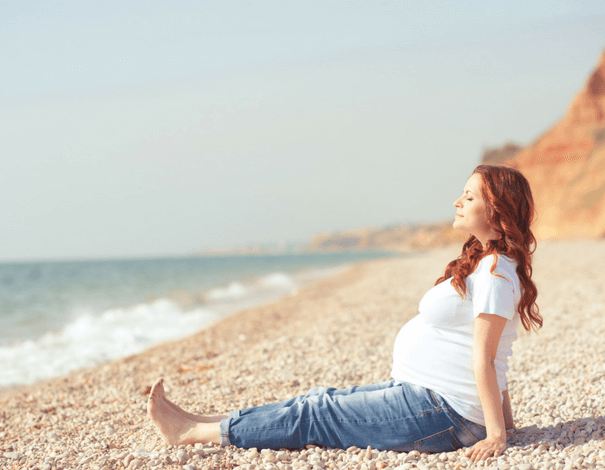 Pregnant woman sitting on the beach Pregnant woman sitting on the beach