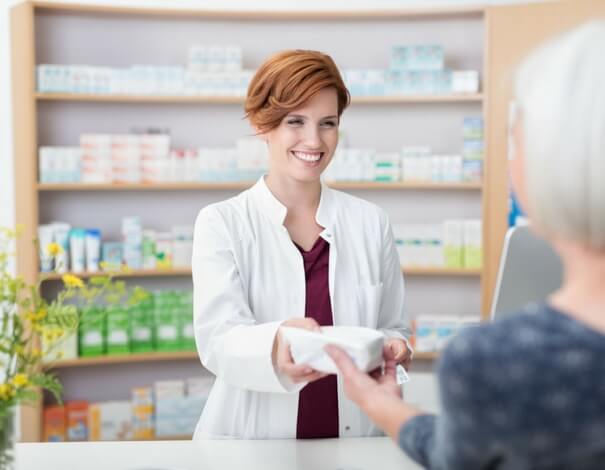 Female pharmacist giving prescription to a female patient, at the pharmacy counter Female pharmacist giving prescription to a female patient